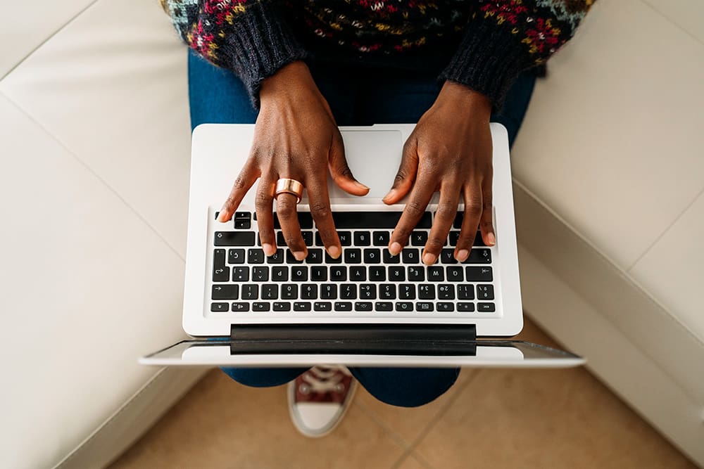 a person sitting on a couch using a laptop writing about an SEO copywriting service